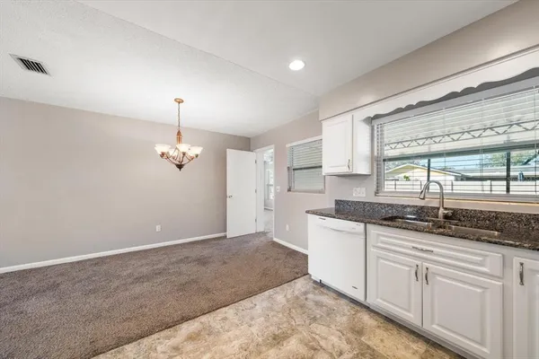 a kitchen with granite countertop kitchen island white cabinets and window