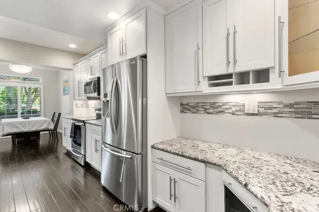a kitchen with granite countertop a refrigerator and microwave