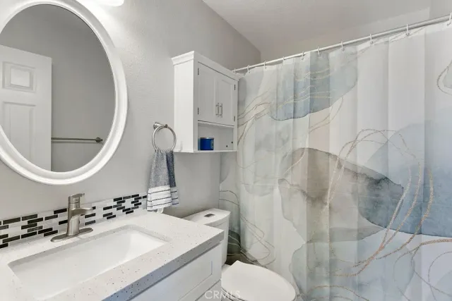 a bathroom with a sink a toilet and a mirror