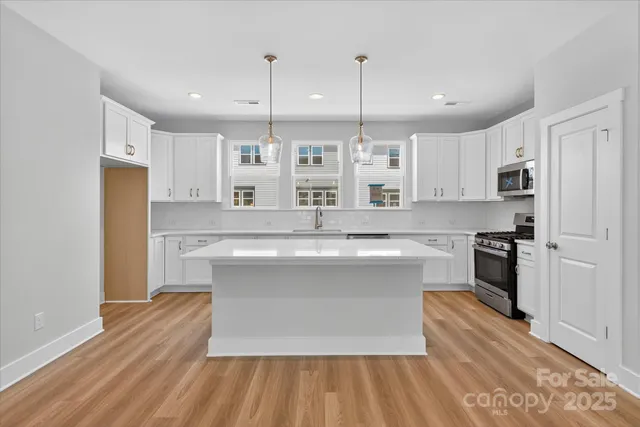 a large kitchen with cabinets wooden floor and stainless steel appliances