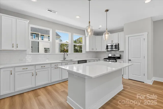 a kitchen with kitchen island granite countertop a sink a stove and a refrigerator