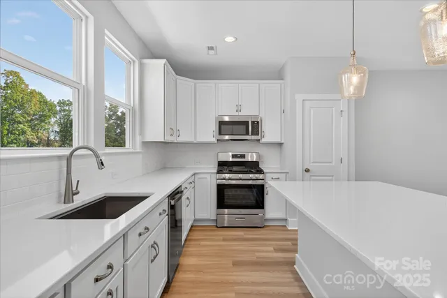 a kitchen with stainless steel appliances granite countertop a sink a stove and a refrigerator