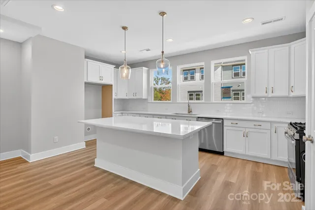 a kitchen with stainless steel appliances granite countertop a sink a stove a refrigerator and island with wooden floor