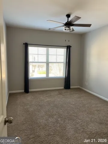 an empty room with a window and a ceiling fan