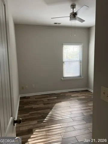 a view of an empty room with wooden floor and a window