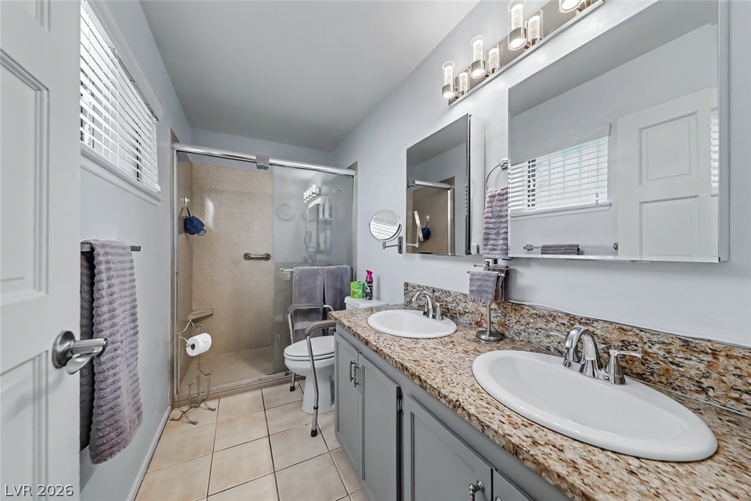 3107 Trueno Road Henderson, NV 89014 - Photo 4 of 37 A well-appointed bath features a double vanity with granite counters and a glass-enclosed shower.