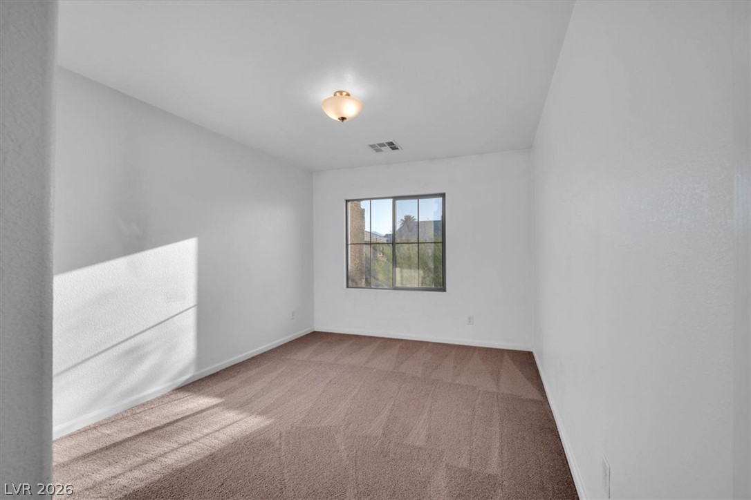 8046 Noble Ridge Street Las Vegas, NV 89139 - Photo 26 of 34 A well-lit bedroom featuring soft carpeting and a window offering outdoor views.