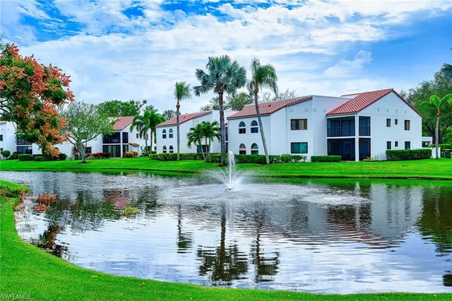 a front view of a house with a garden and lake view
