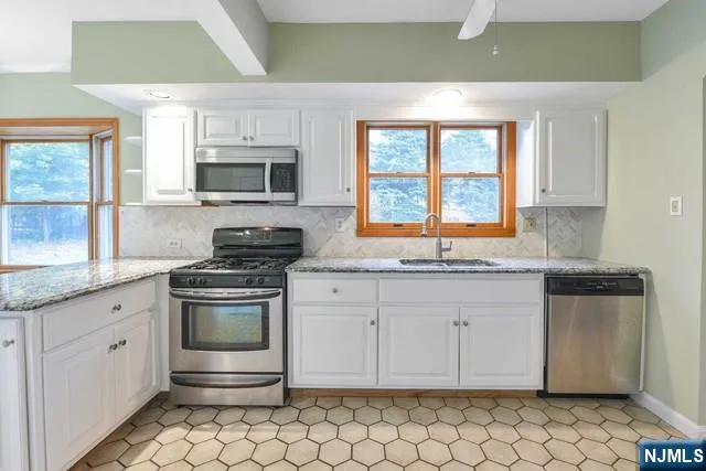 a kitchen with stainless steel appliances granite countertop a stove a sink and a microwave