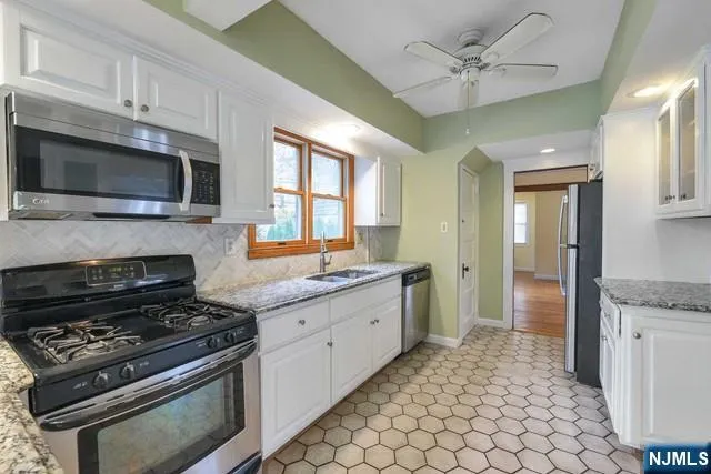 a kitchen with granite countertop a stove sink and microwave