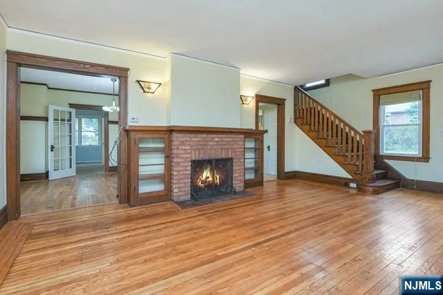 a view of a livingroom with wooden floor a fireplace and entryway