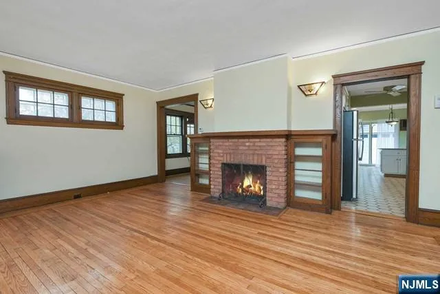 a view of an empty room with wooden floor fireplace and a window