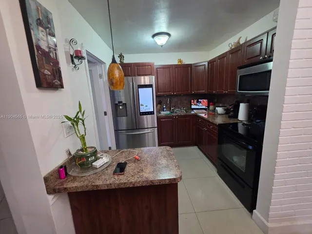 a kitchen with kitchen island granite countertop stainless steel appliances and wood cabinets