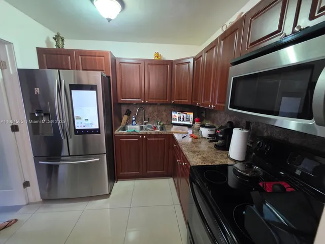 a kitchen with granite countertop wooden cabinets and stainless steel appliances