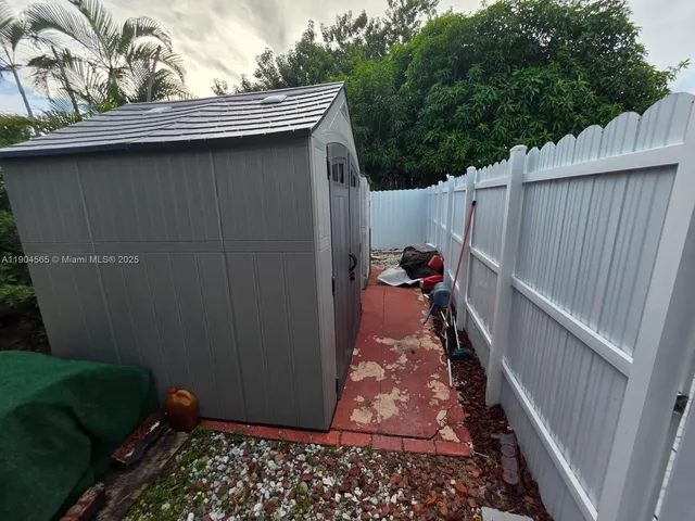 a backyard of a house with large tree and wooden fence