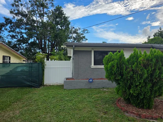 a view of a backyard with plants and a large tree