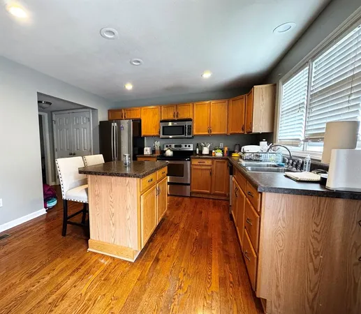 a large kitchen with stainless steel appliances kitchen island granite countertop a stove a sink dishwasher and a refrigerator