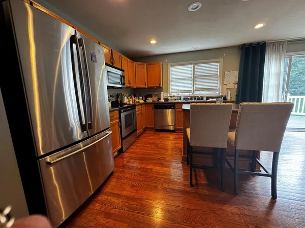a kitchen with stainless steel appliances granite countertop a refrigerator a stove a sink dishwasher a dining table and chairs with wooden floor