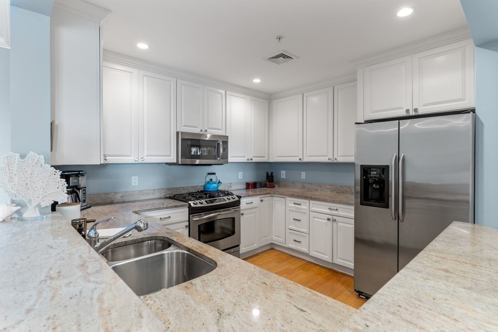 39 Intrepid Circle, Unit 302 Marblehead, MA 01945 - Photo 9 of 32 a kitchen with granite countertop a refrigerator sink and white cabinets