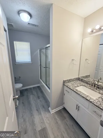 a bathroom with a granite countertop sink a toilet a mirror and vanity