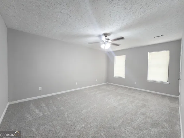a view of an empty room with a chandelier fan