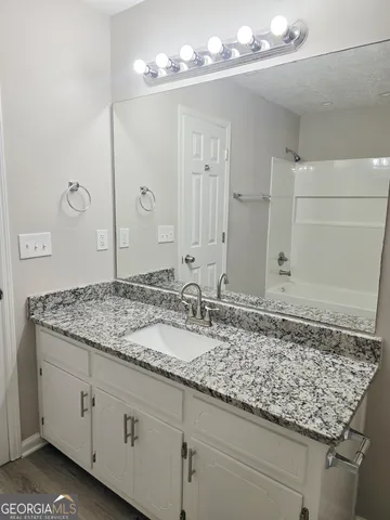 a bathroom with a granite countertop sink and a mirror