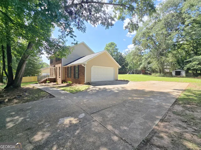 a view of a house with a yard and large trees