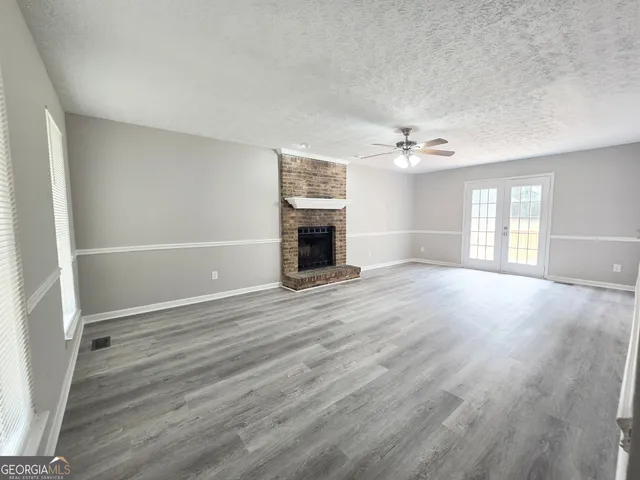 an empty room with windows and a ceiling fan
