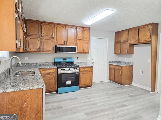 a kitchen with granite countertop a stove top oven sink and cabinets