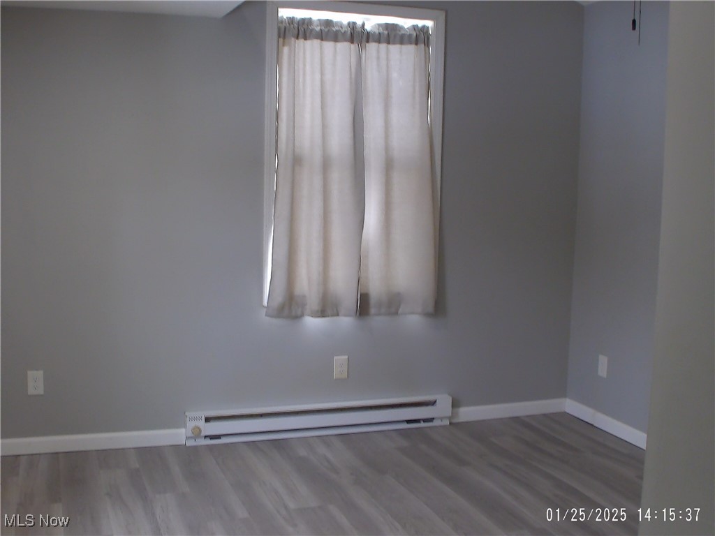 10100 Dresden Road Dresden, OH 43821 - Photo 6 of 7 Unfurnished room with hardwood / wood-style flooring and a baseboard radiator