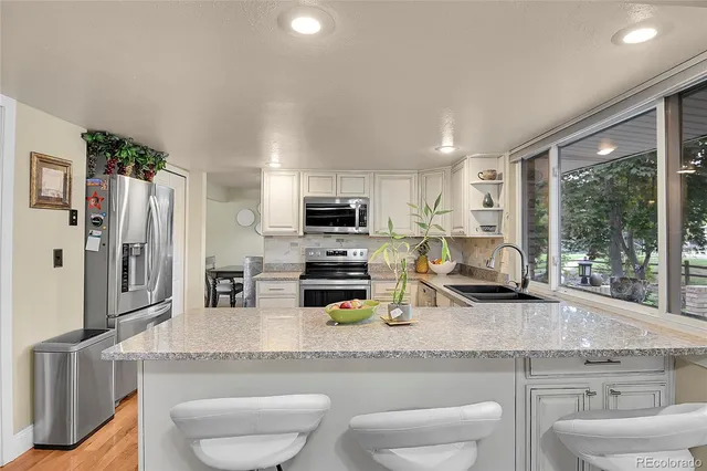 a kitchen with sink a stove and chairs
