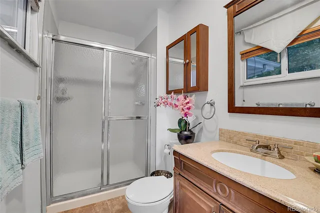 a bathroom with a granite countertop sink toilet mirror and shower