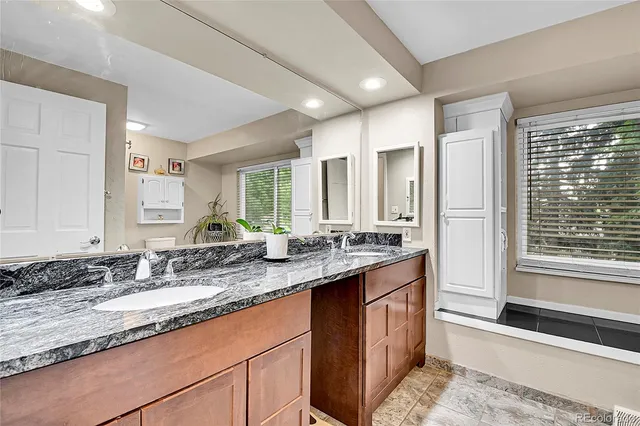 a bathroom with a granite countertop sink and a large mirror