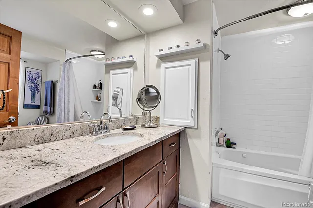a bathroom with a granite countertop sink mirror and a bath tub