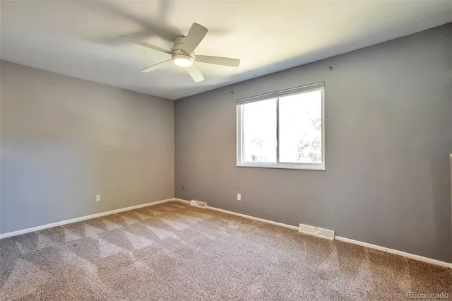 an empty room with a window and a fan