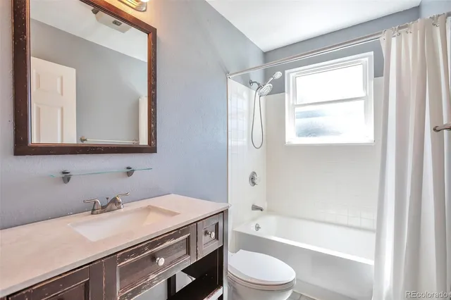 a bathroom with a granite countertop sink a toilet a mirror and a bathtub