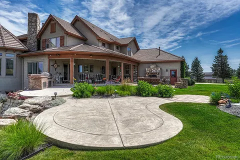 a view of a white house with a yard potted plants and large tree
