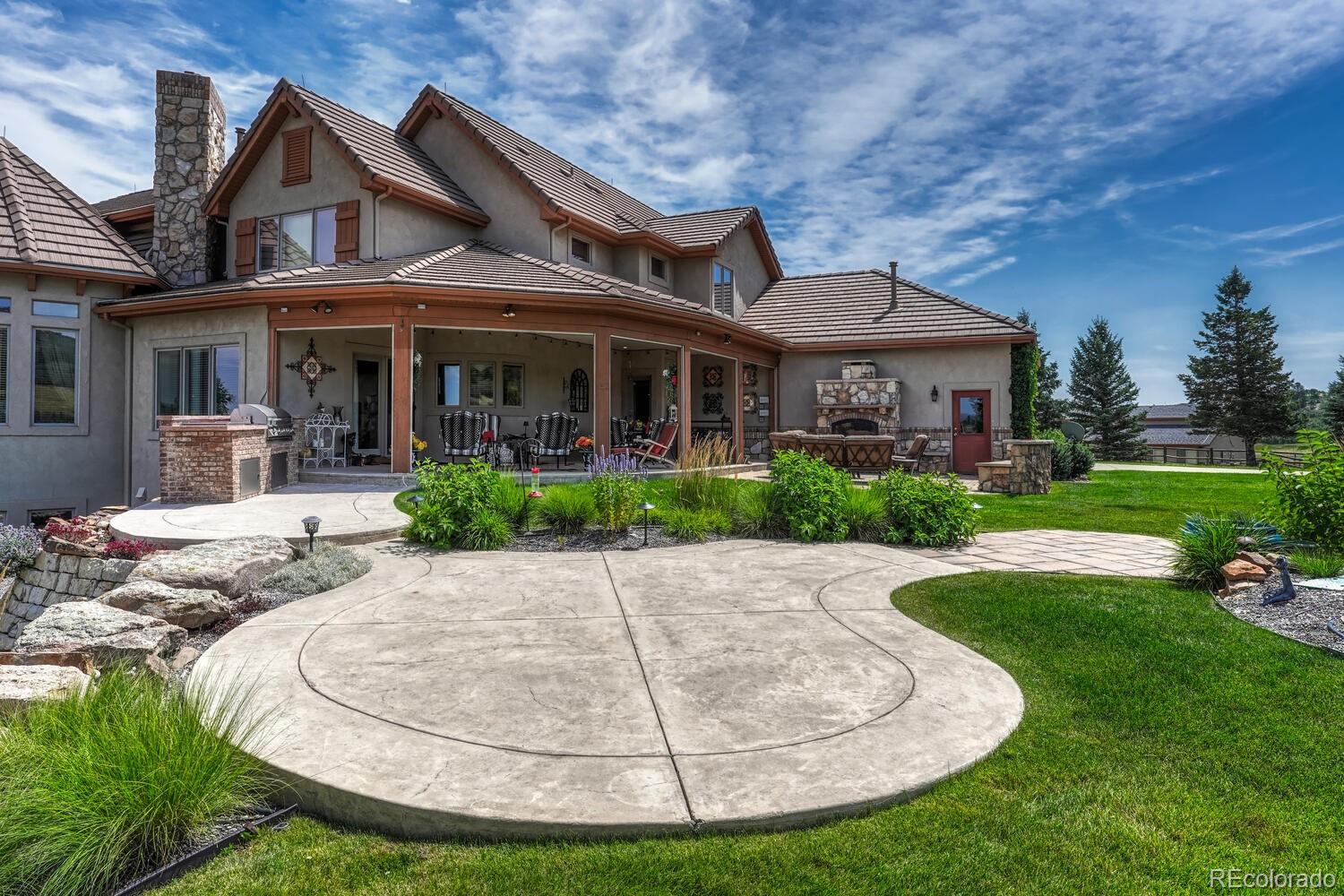3851 Castle Butte Drive Castle Rock, CO 80109 - Photo 43 of 50 a view of a white house with a yard potted plants and large tree