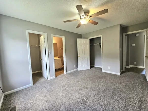 an empty room with closet and a ceiling fan