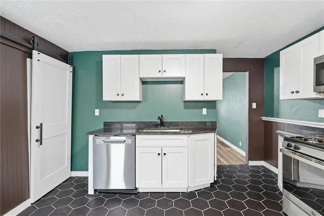 a kitchen with granite countertop a stove a sink and a refrigerator
