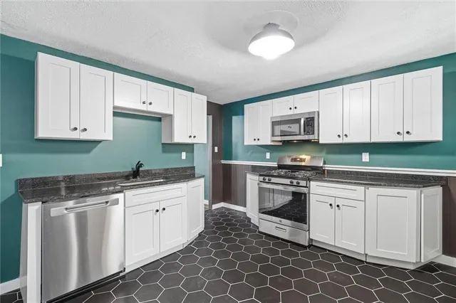 a kitchen with stainless steel appliances granite countertop a stove a sink and a microwave