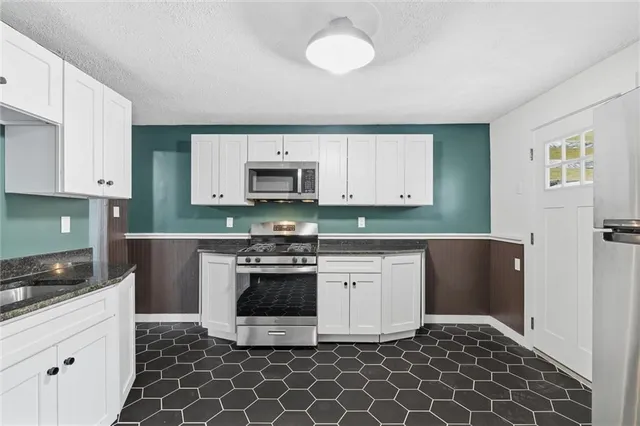 a kitchen with granite countertop a stove a sink and a microwave