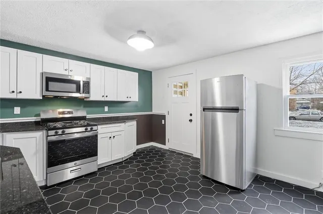 a kitchen with stainless steel appliances granite countertop a refrigerator sink and stove