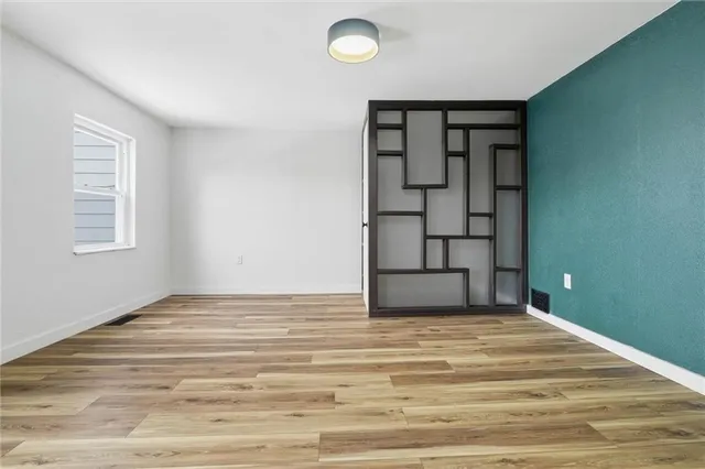 a view of an empty room with window and wooden floor