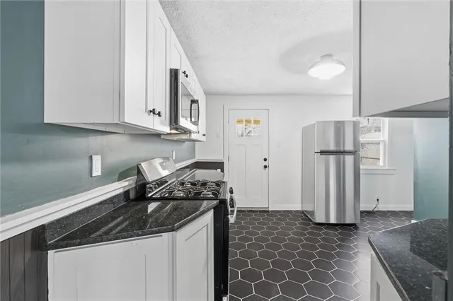 a kitchen with stainless steel appliances granite countertop a refrigerator a stove and a sink