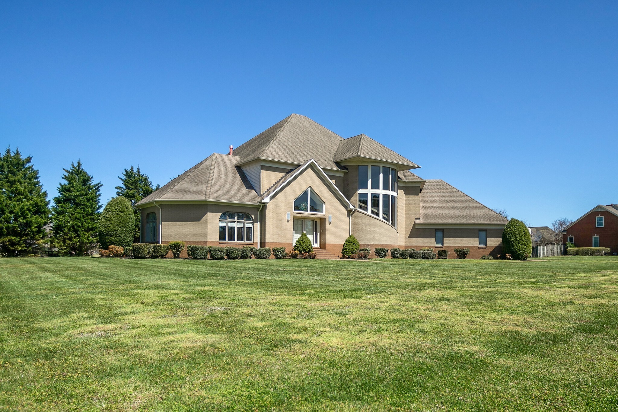 a house that is sitting in the grass with large trees