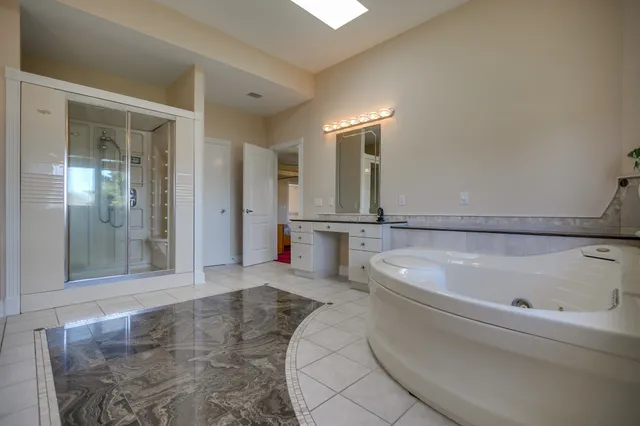 a spacious bathroom with a tub sink and mirror