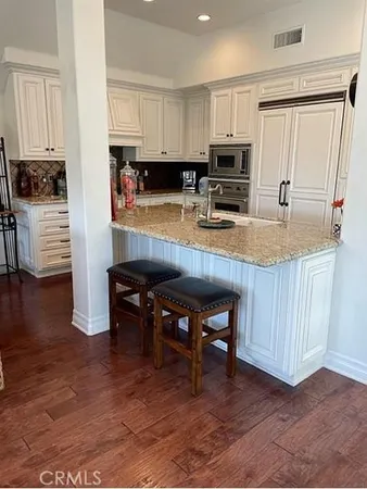 a kitchen with stainless steel appliances granite countertop a stove top oven a sink a dining table and chairs with wooden floor