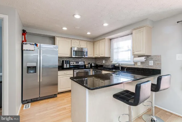 a kitchen with granite countertop kitchen island stainless steel appliances a refrigerator a stove a sink counter space and a center island