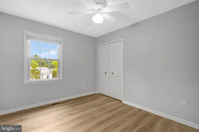 a view of an empty room with window and wooden floor